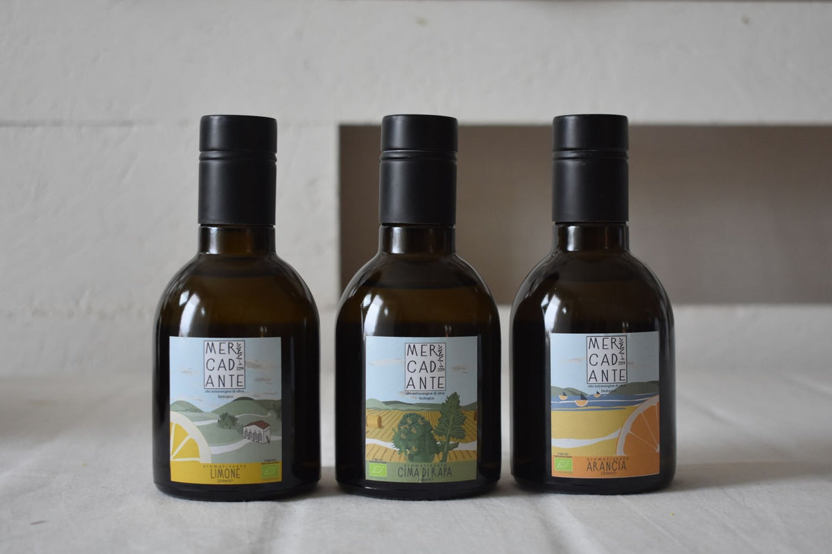 Tre bottiglie di olio Mercadante con le etichette illustrate